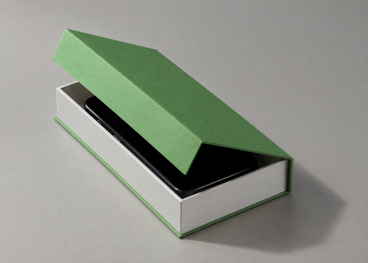 A green and grey rigid box with its hinged lid partly open and a black smartphone in the tray.